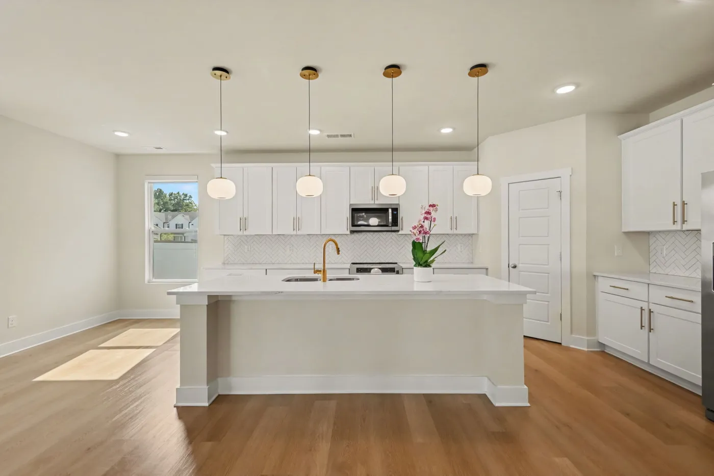 Kitchen with white shaker cabinets, stainless microwave, and a large center island