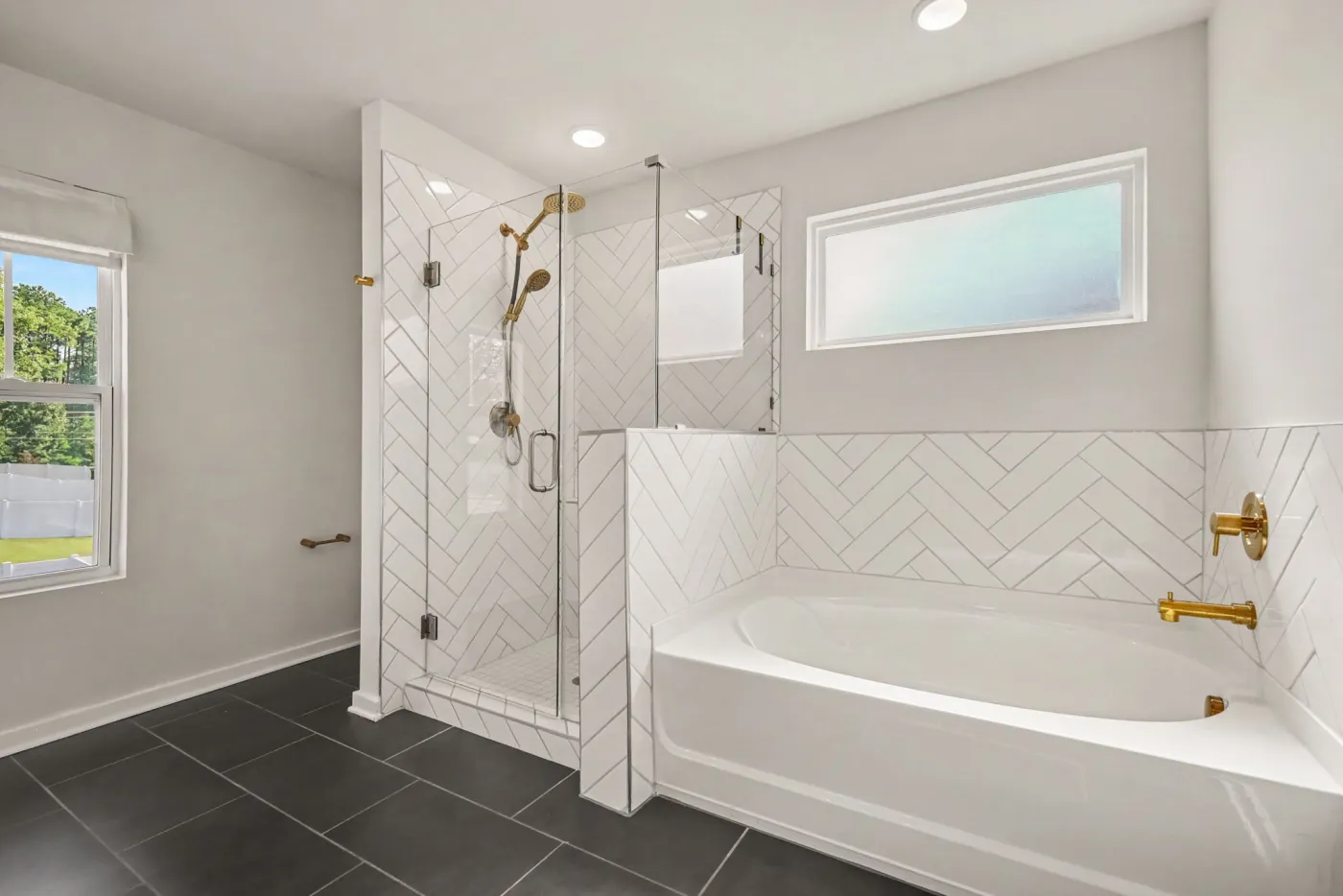 Primary bath with a glass walk-in shower and soaking tub with herringbone tile