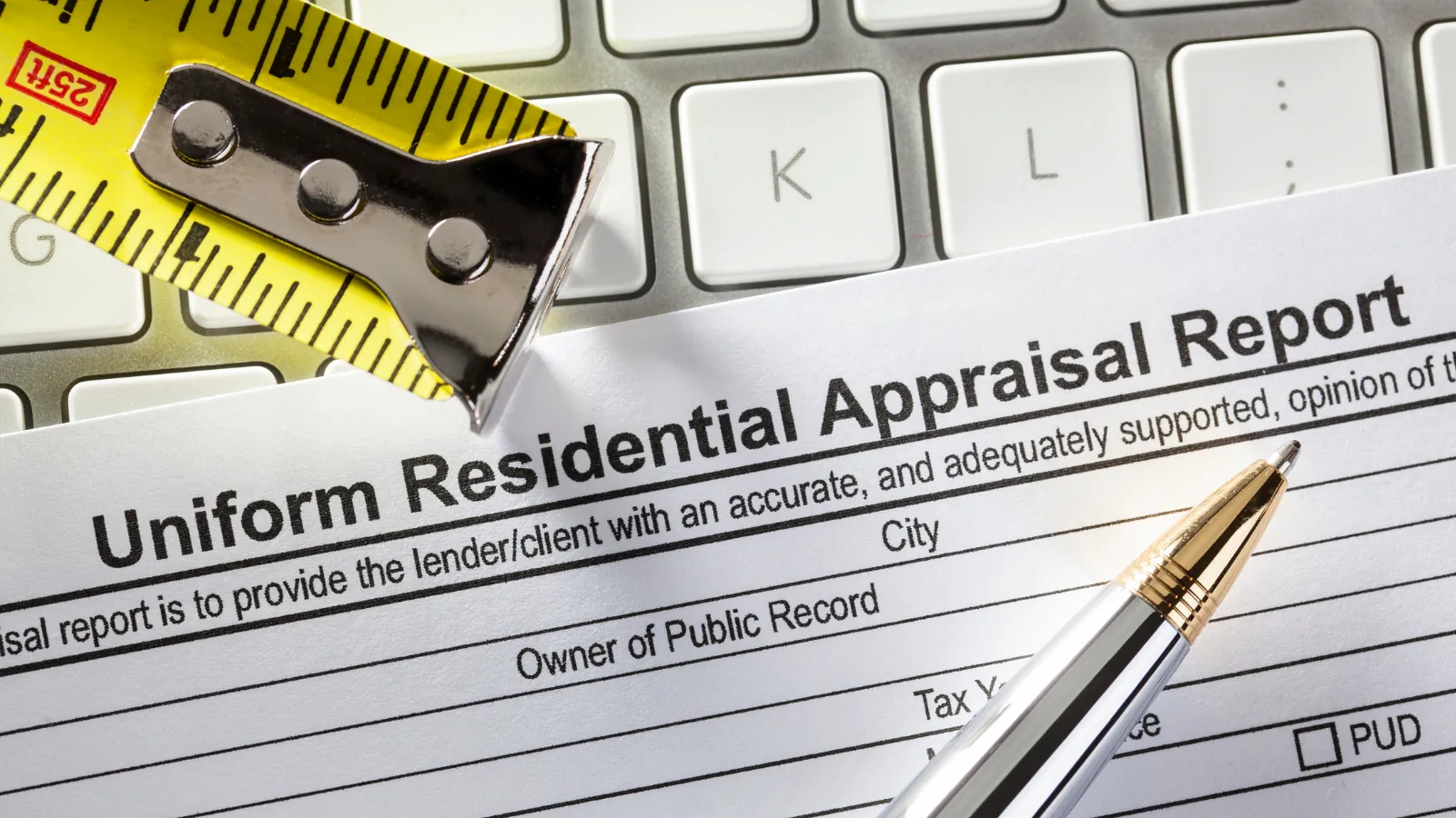 A Uniform Residential Appraisal Report form with a tape measure and a pen resting on it